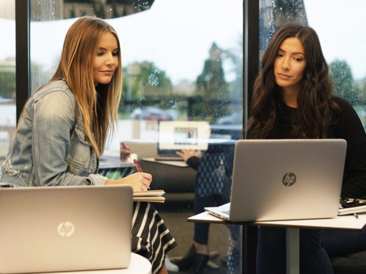 Pictured are two Tweezerman employees working with notebook and at their laptops